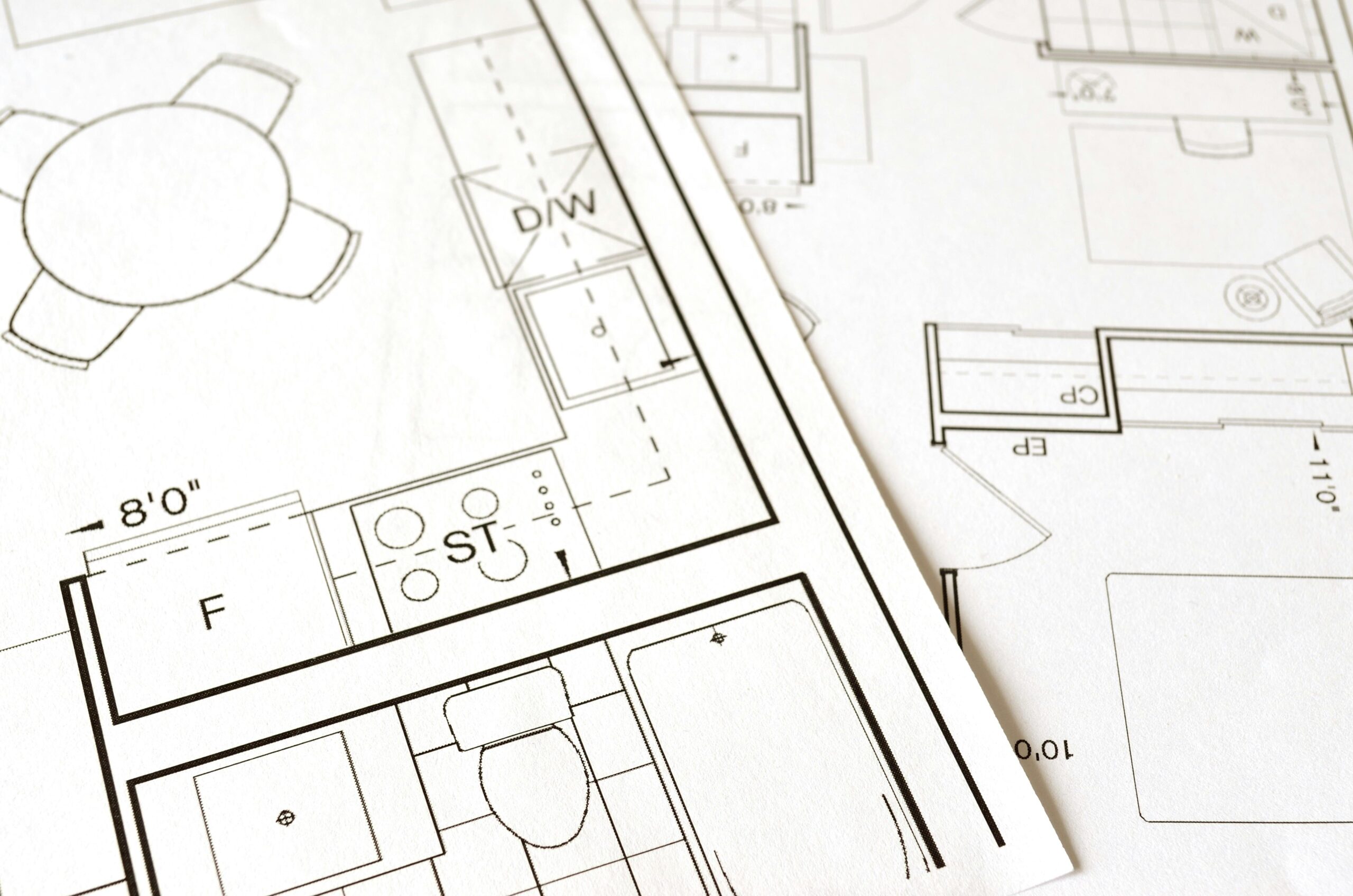 Affordable Interiors In Hyderabad Close-up view of an architectural floor plan on paper showcasing detailed room layouts and measurements.
